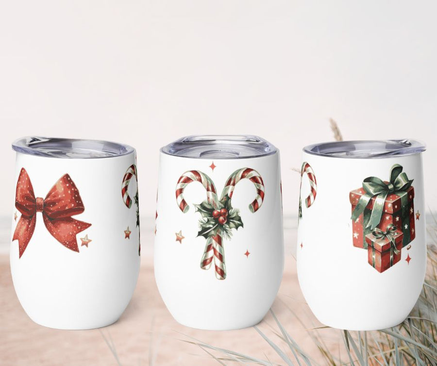 Three white tumblers with Christmas-themed designs on a beige surface.