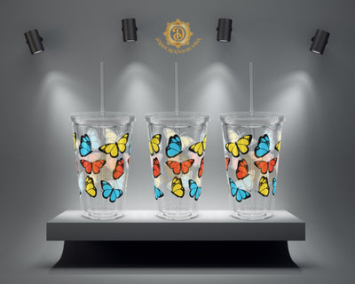 Three clear tumblers with colourful butterfly designs on a grey platform with spotlights.