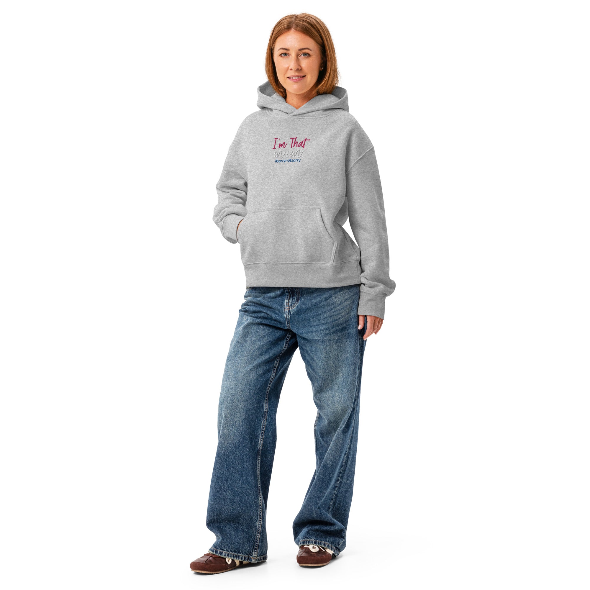 Person wearing a grey hoodie with text and blue jeans on a white background