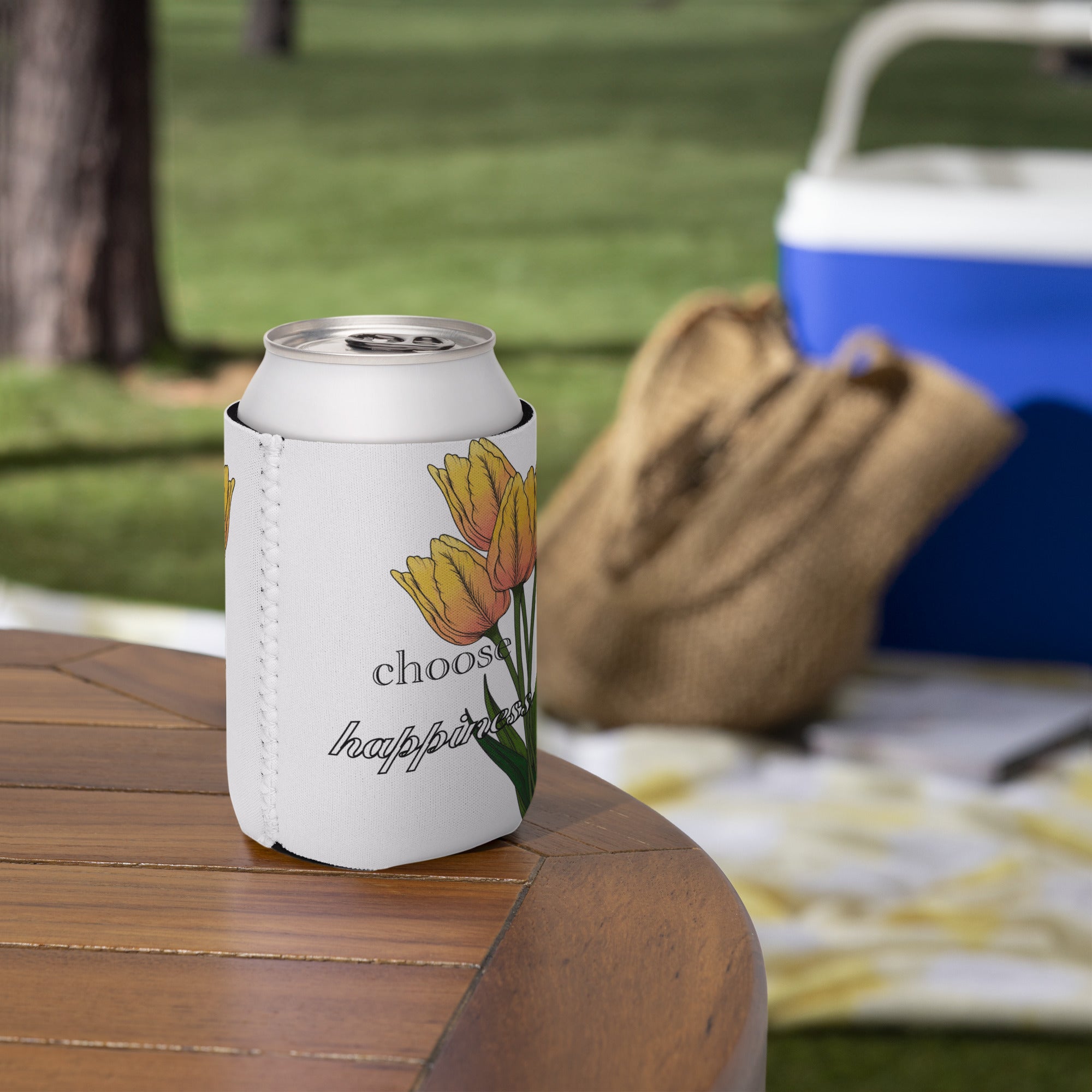 Can cooler with floral design and 'choose happiness' text on a wooden table outdoors.