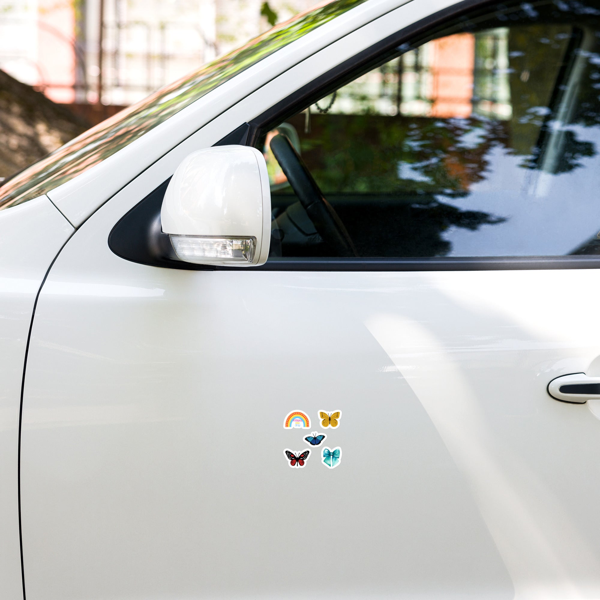 Colourful butterfly and rainbow stickers on a white car door.
