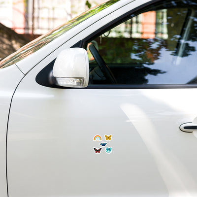 Colourful butterfly and rainbow stickers on a white car door.