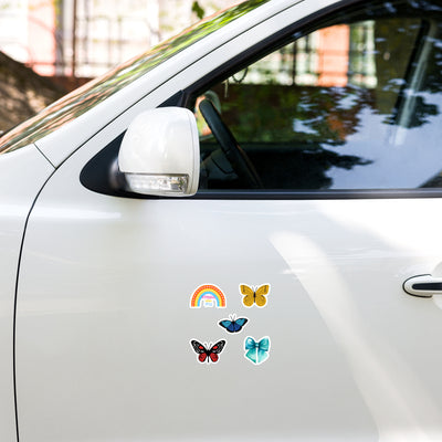 Kiss cut rainbow, butterfly and bow stickers on a white car door with a white background.