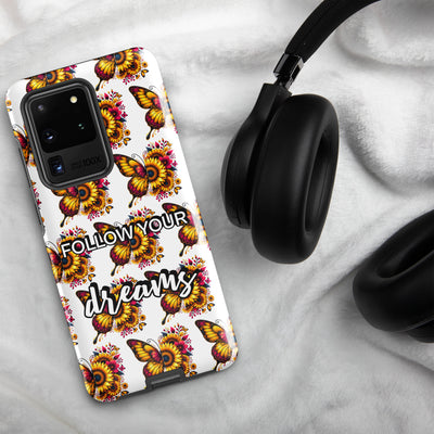 Phone case with butterfly design and 'Follow your dreams' text on a marble surface with headphones.