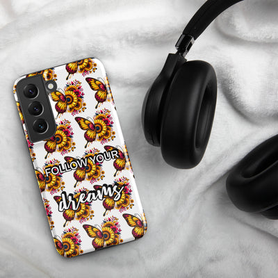 Phone case with butterfly design and 'Follow Your Dreams' text on a marble surface with headphones.