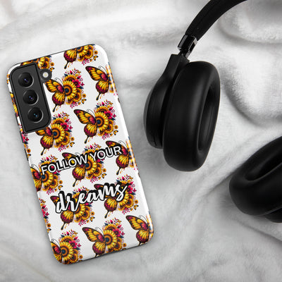Phone case with butterfly design and 'Follow your dreams' text on a marble surface with headphones.