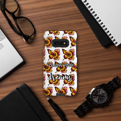 Phone case with butterfly design and 'Follow Your Dreams' text on a wooden desk with accessories.