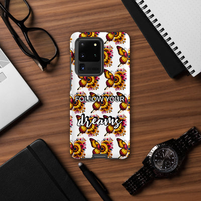 Phone case with butterfly design and 'Follow Your Dreams' text on a wooden desk.