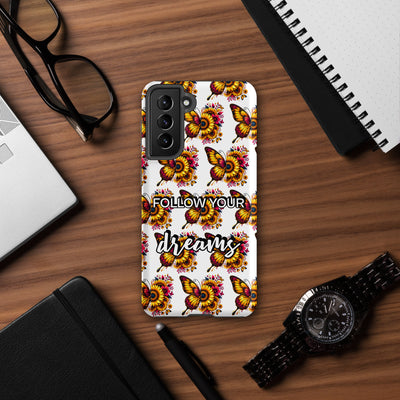 Phone case with butterfly design and 'Follow your dreams' text on a wooden desk.