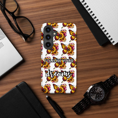 Phone case with butterfly design and 'Follow Your Dreams' text on a wooden surface with accessories.