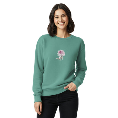 Woman wearing a teal sweatshirt with a floral design on a white background