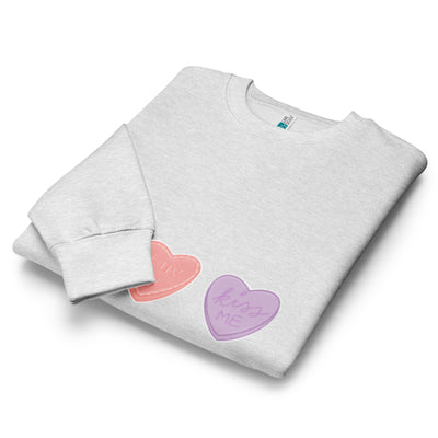 Folded grey sweatshirt with colourful heart designs on a white background