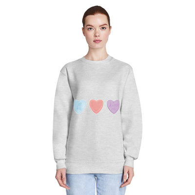 Person wearing a grey sweatshirt with colourful heart designs on a white background
