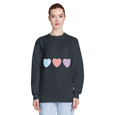 Person wearing a black sweatshirt with colourful heart designs on a white background
