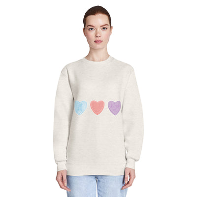 Person wearing a light coloured sweatshirt with colourful heart designs on a white background
