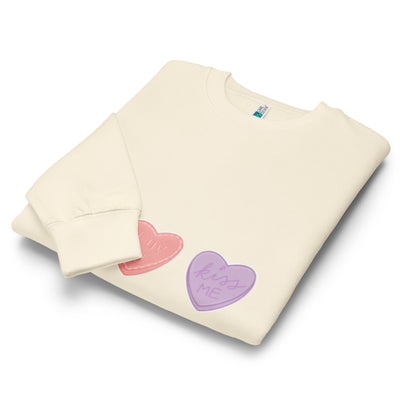 Folded cream-coloured sweatshirt with colourful heart-shaped designs on a white background