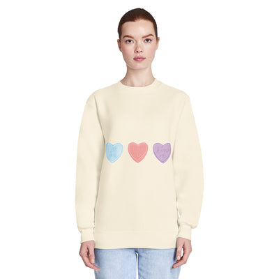 Woman wearing a light yellow sweater with colourful heart patterns on a white background