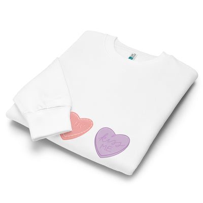 Folded white sweatshirt with colourful heart designs on a white background