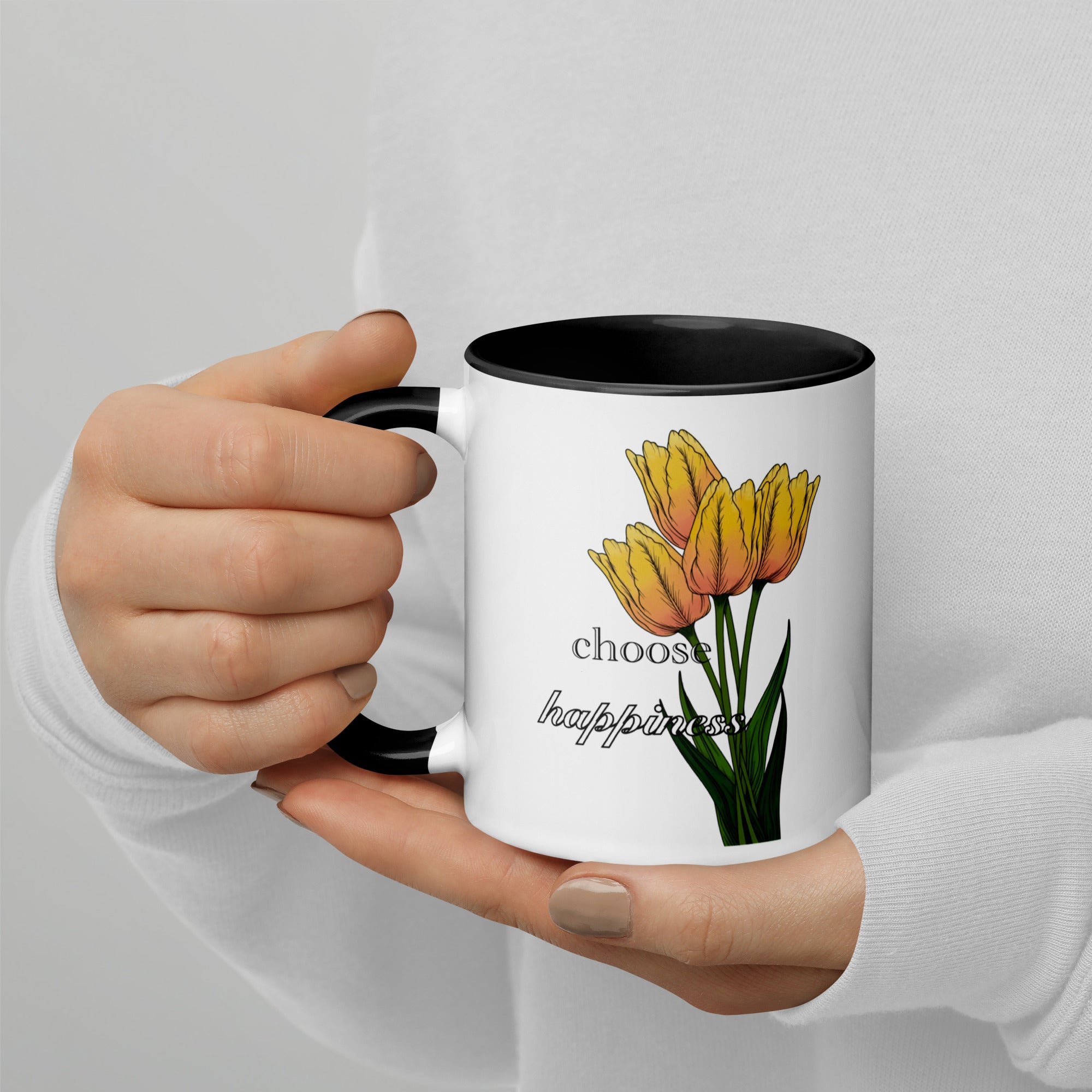 Hand holding a mug with yellow tulips and 'choose happiness' text on a light gray background