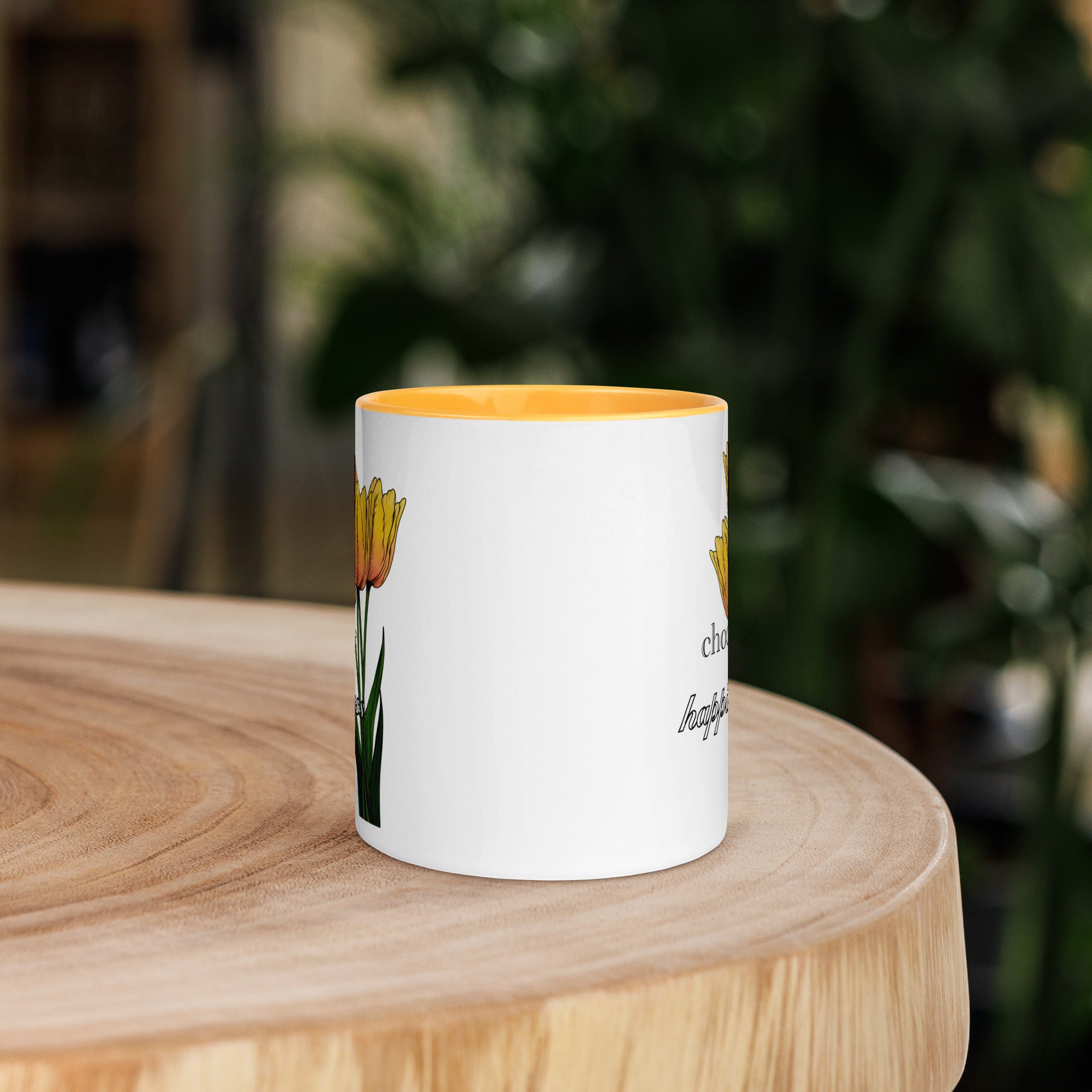 White mug with yellow interior and floral design on a wooden surface