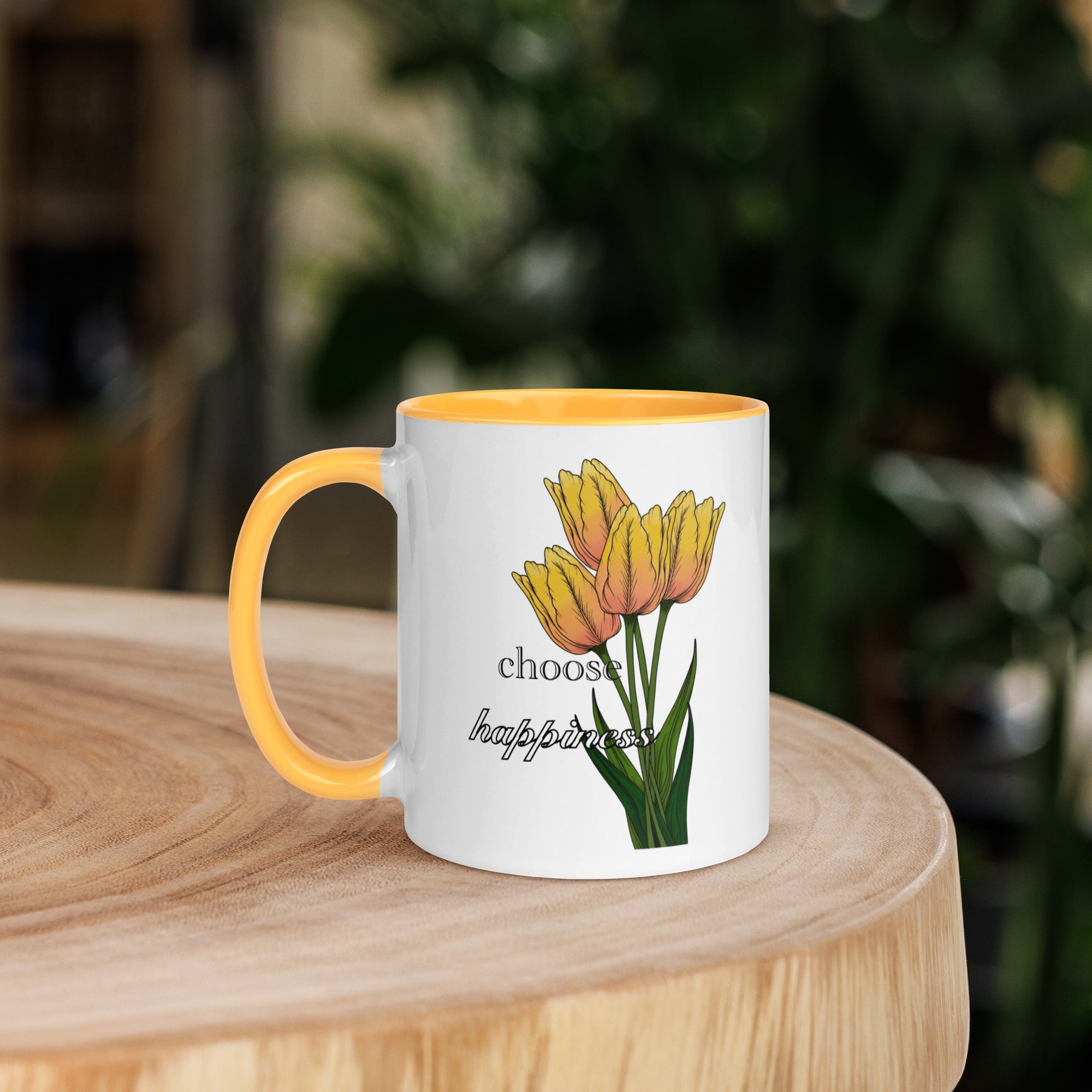 Mug with yellow tulips design and 'choose beauty over fear' text on a wooden surface.