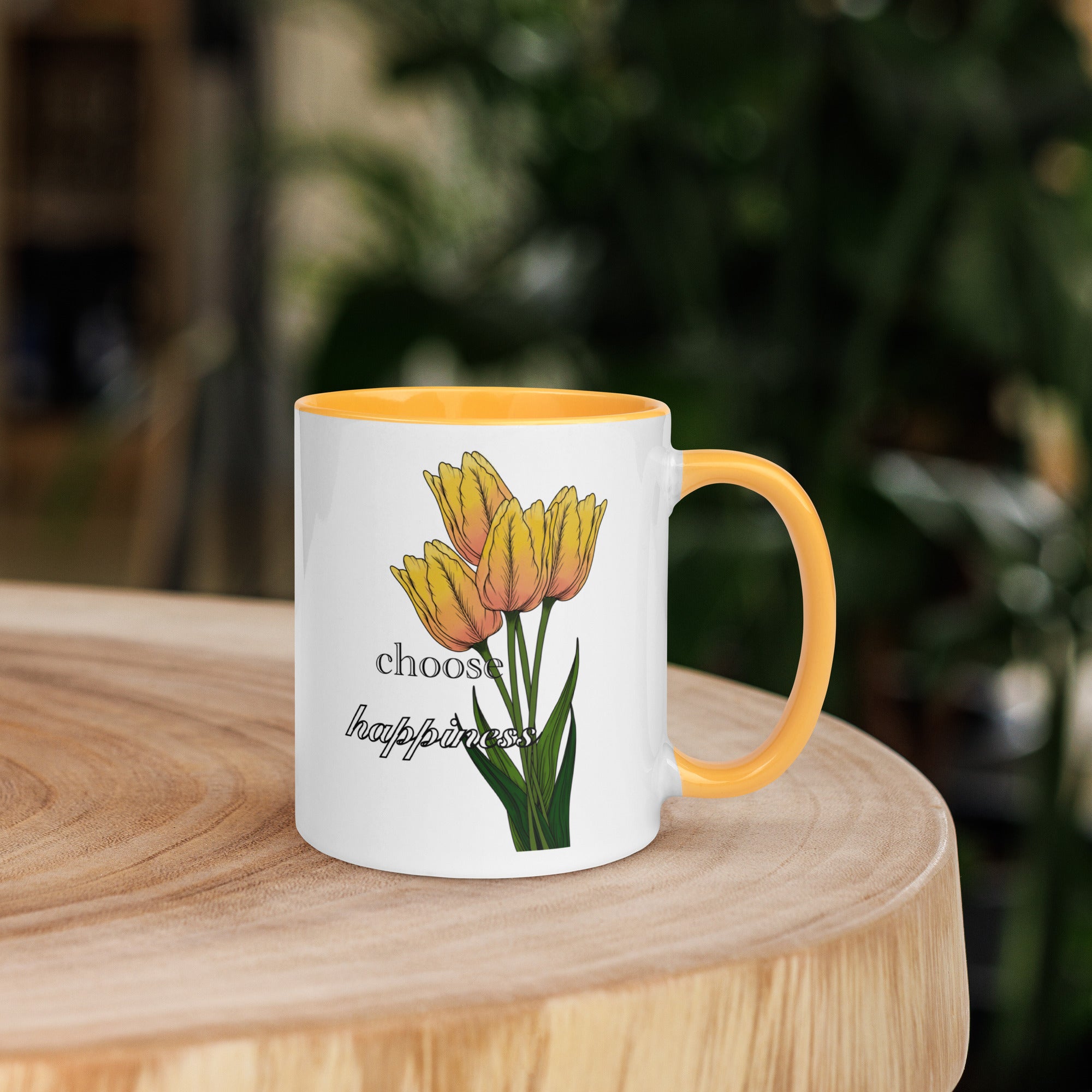Mug with yellow tulips design and 'choose beauty over fear' text on a wooden surface.