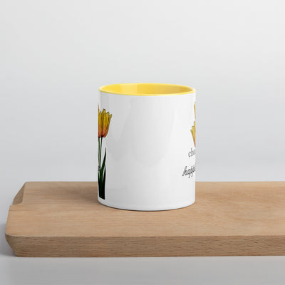 White mug with yellow interior and floral design on a wooden surface