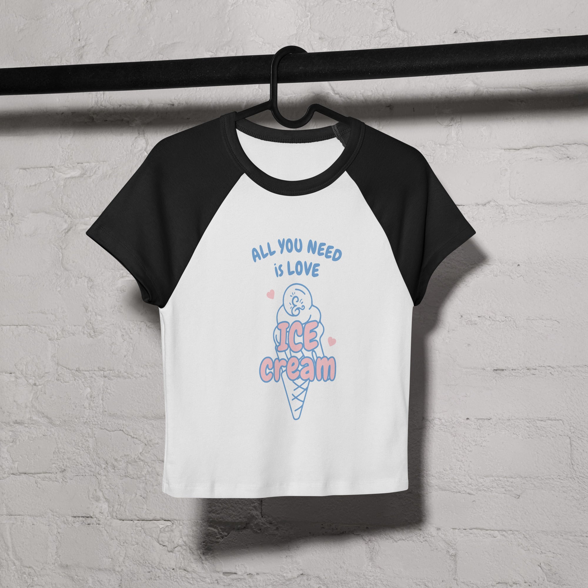 Black and white baseball shirt with ice cream graphic and text on a hanger against a textured wall.