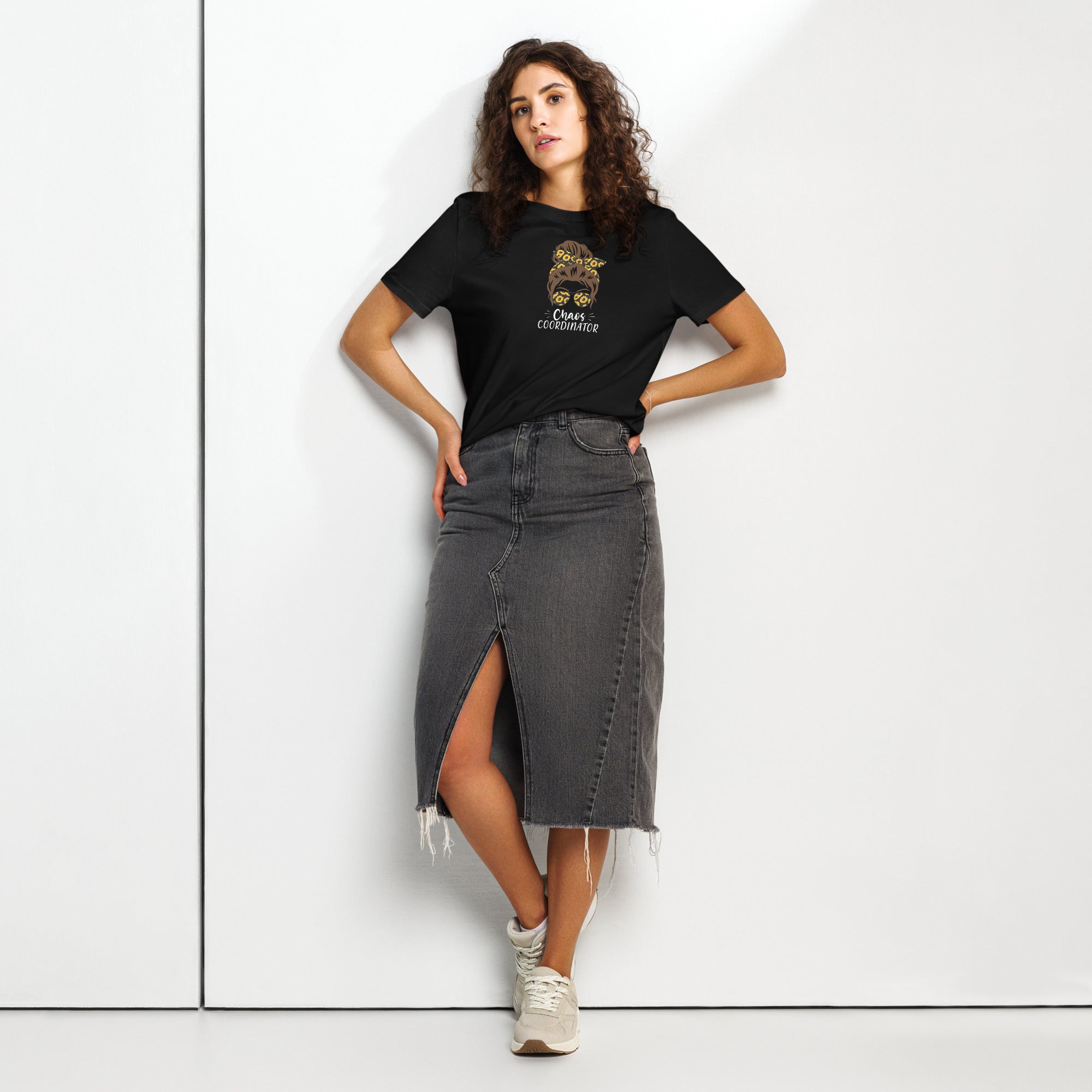 Woman wearing a black t-shirt with a girl logo and 'Chaos Co-ordinator' text, and a black denim skirt on a white background
