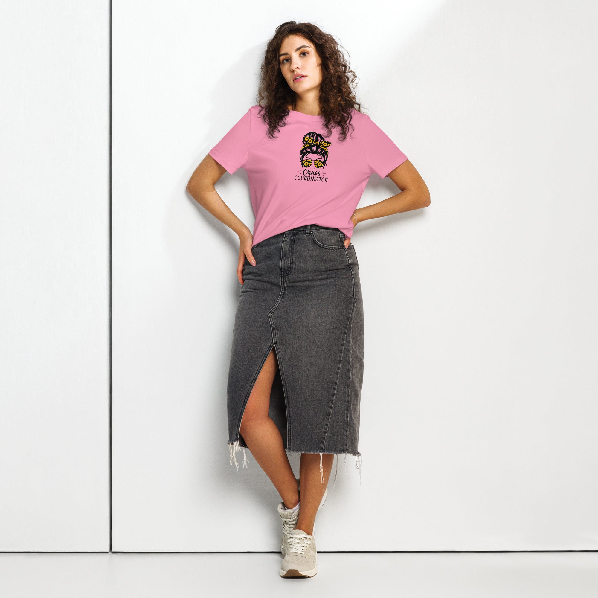 Woman wearing a pink t-shirt with a graphic girl design and a black denim skirt on a white background