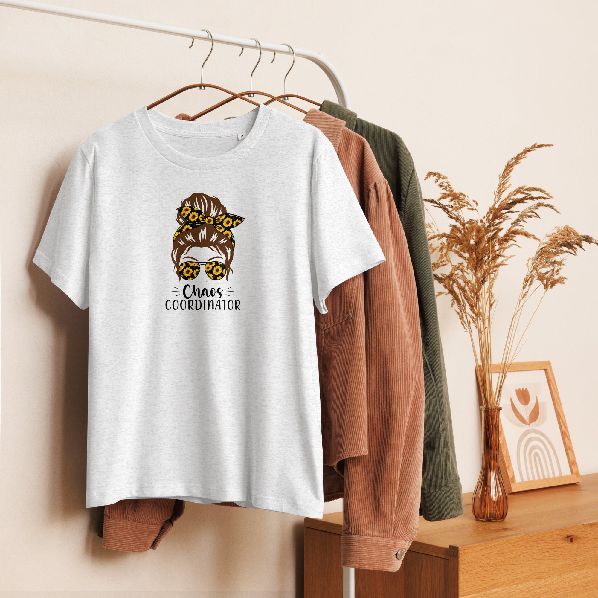 White t-shirt with graphic design hanging on a rack with other clothes.