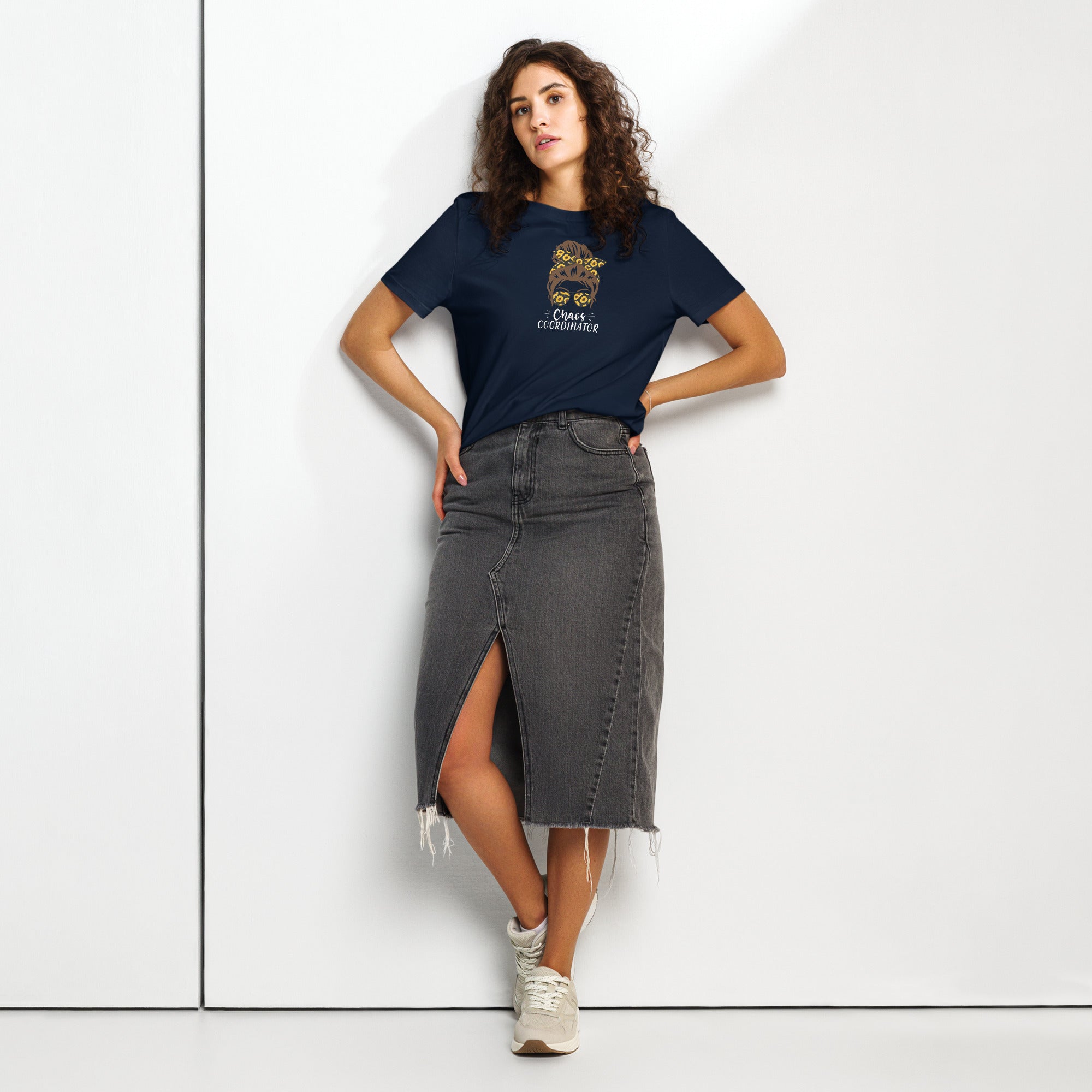 Woman wearing a navy t-shirt with a girl logo and a black denim skirt on a white background