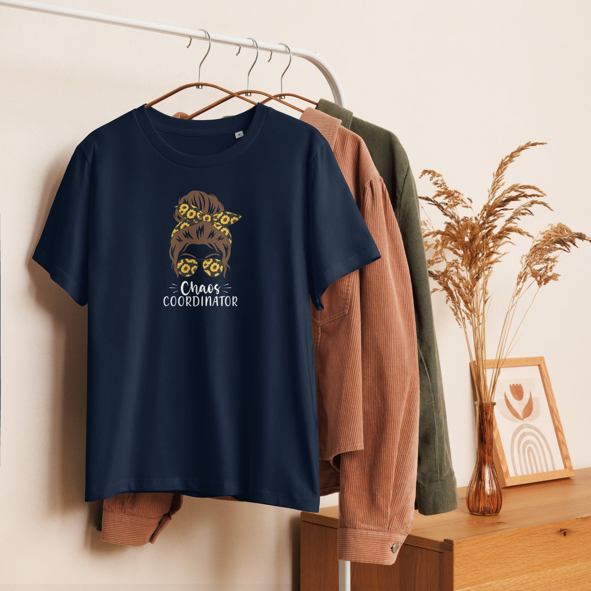 Navy blue t-shirt with graphic girl design and 'Chaos Co-ordinator' text on a hanger against a neutral background.