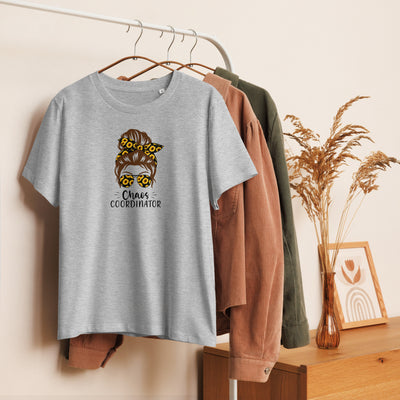 Gray t-shirt with a graphic design and 'Chaos Co-ordinator' text on a hanger against a wall with other clothing items