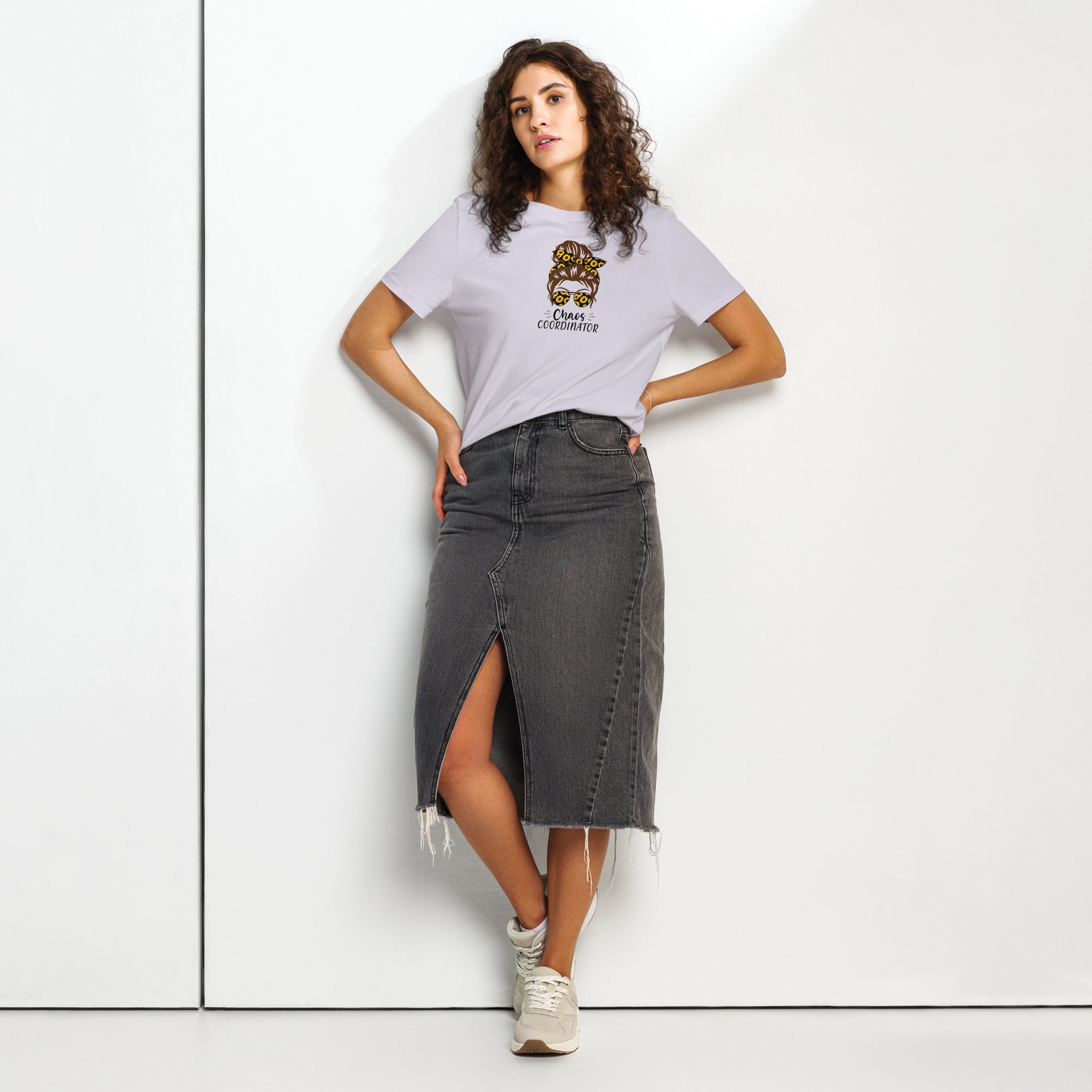 Woman wearing a purple t-shirt with a logo and 'Chaos Co-ordinator' text and a black denim skirt on a white background